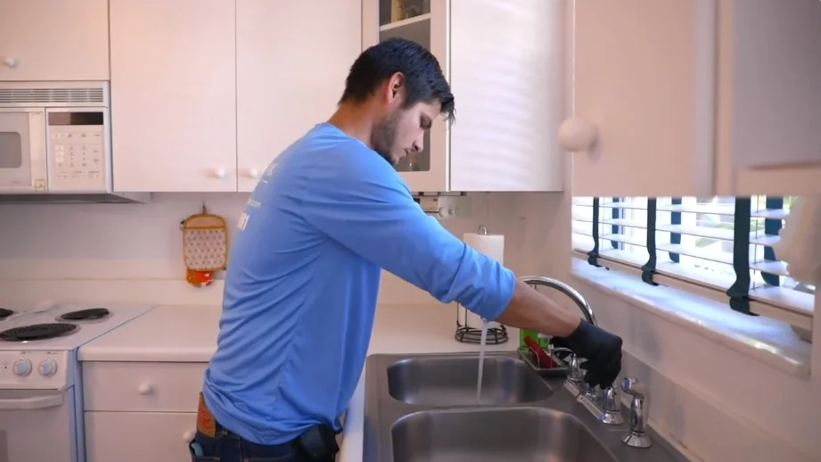 Homeowner checking a kitchen faucet before a water meter leak test