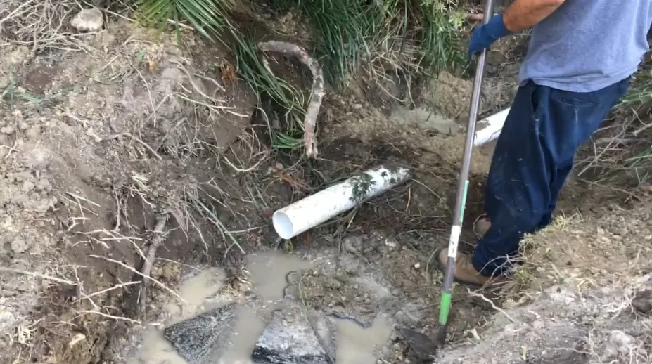 Small excavation exposing a water service line at a located leak
